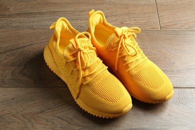 Photo of Pair of stylish yellow sneakers on wooden background