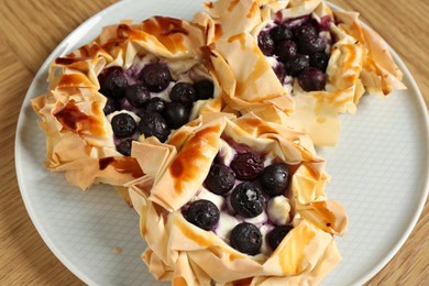 Photo of Delicious puff pastries with blueberries on wooden table, closeup