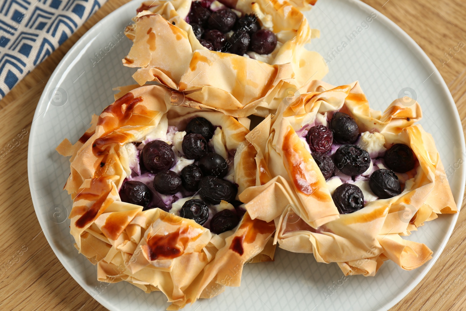 Photo of Delicious puff pastries with blueberries on wooden table, top view