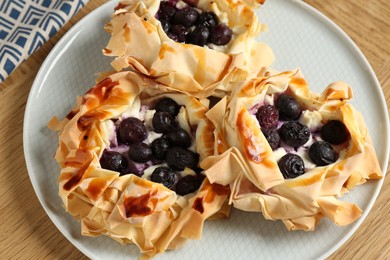 Photo of Delicious puff pastries with blueberries on wooden table, top view