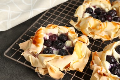 Photo of Delicious puff pastries with blueberries on gray textured table, closeup