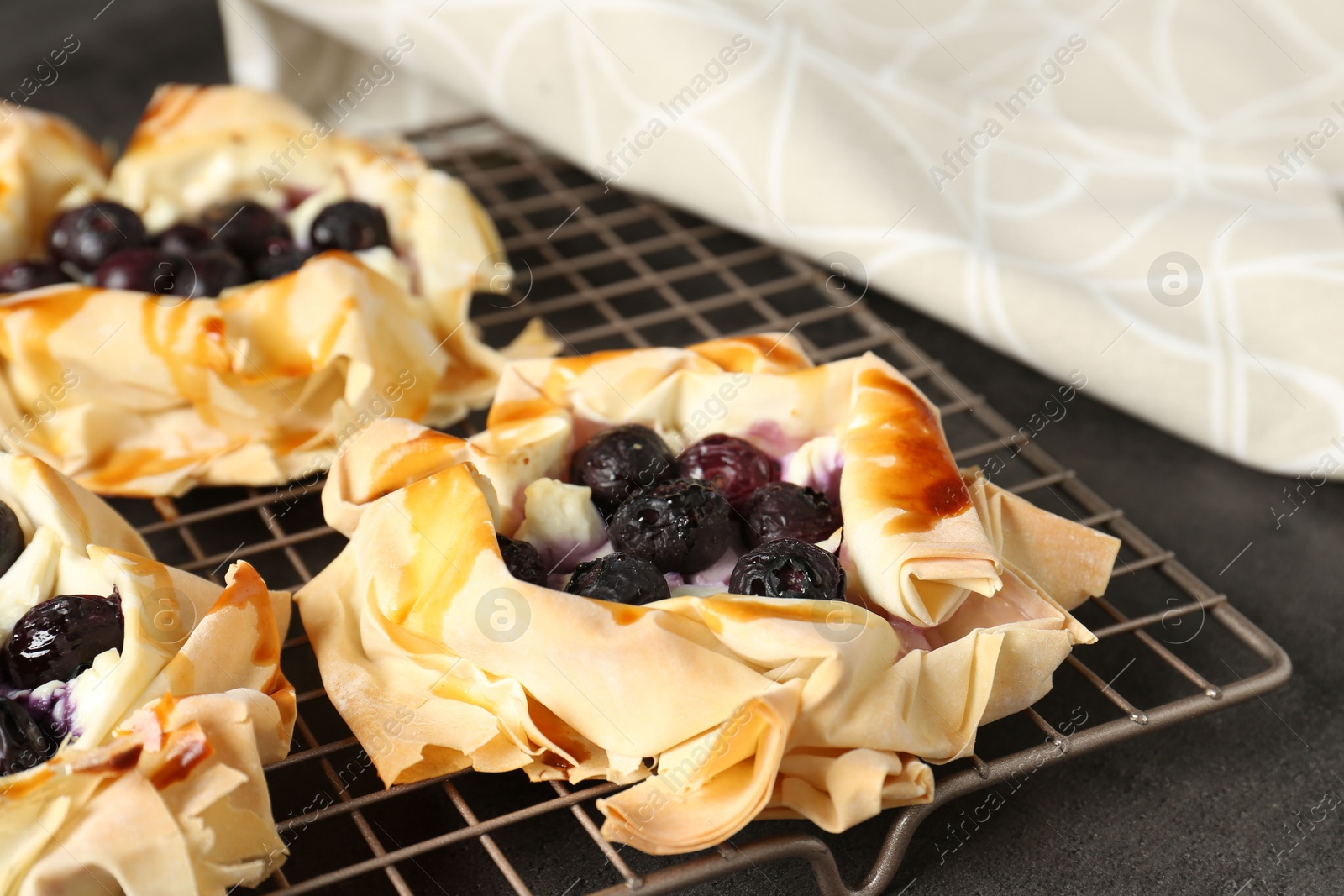 Photo of Delicious puff pastries with blueberries on gray textured table, closeup