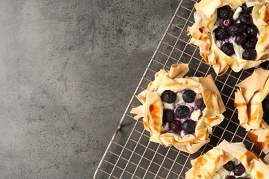 Photo of Delicious puff pastries with blueberries on gray textured table, top view. Space for text