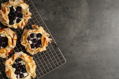 Photo of Delicious puff pastries with blueberries on gray textured table, top view. Space for text