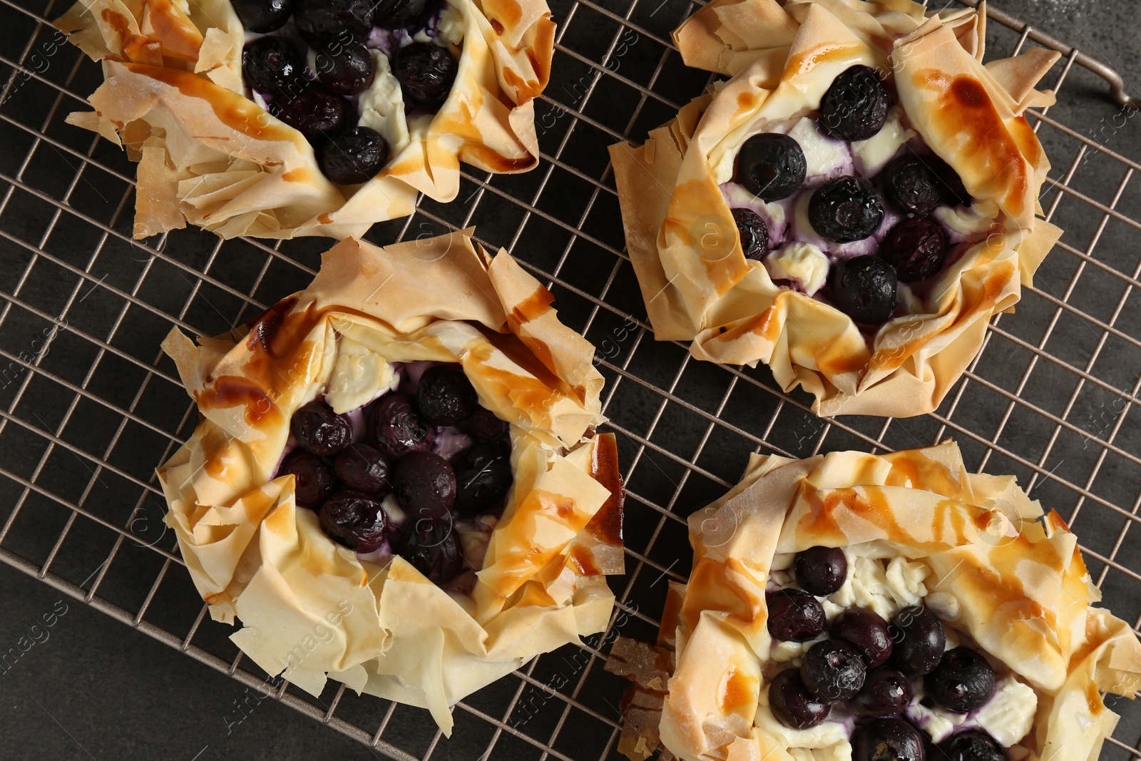 Photo of Delicious puff pastries with blueberries on gray textured table, top view