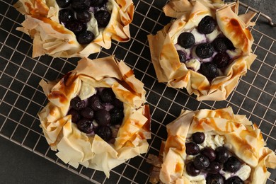 Photo of Delicious puff pastries with blueberries on gray textured table, top view