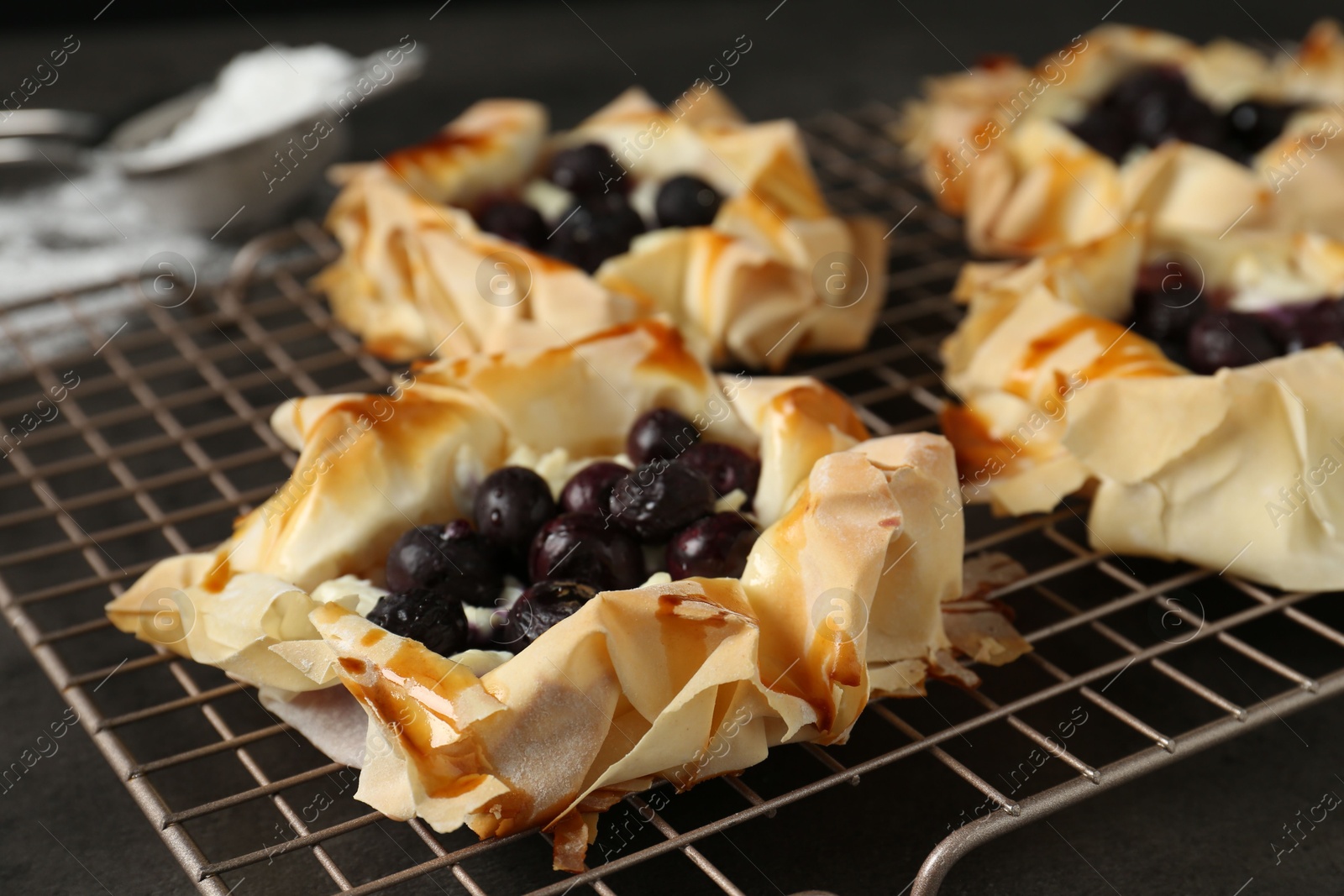 Photo of Delicious puff pastries with blueberries on gray textured table, closeup