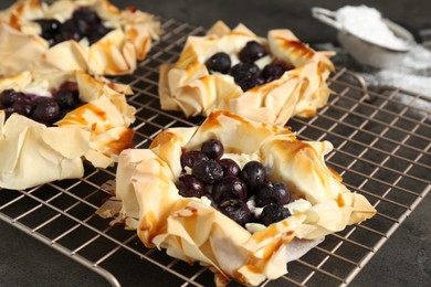 Photo of Delicious puff pastries with blueberries on gray textured table, closeup