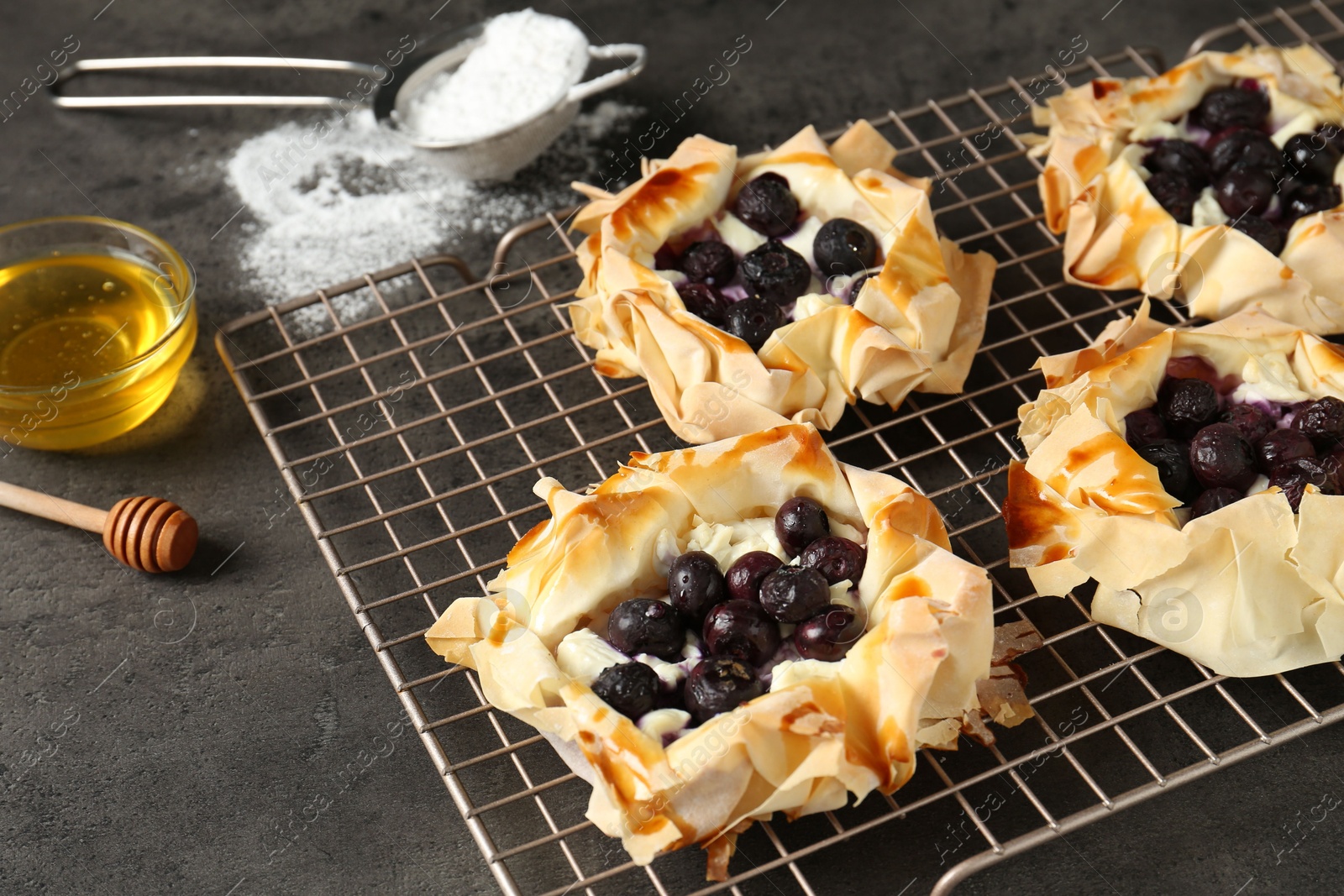 Photo of Delicious puff pastries with blueberries on gray textured table, closeup