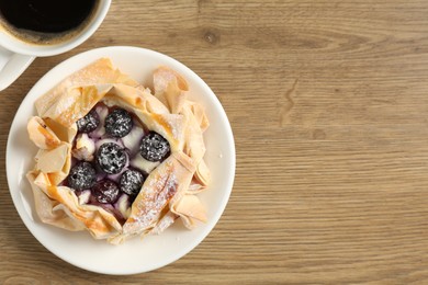 Photo of Tasty puff pastry with blueberries and coffee on wooden table, top view. Space for text