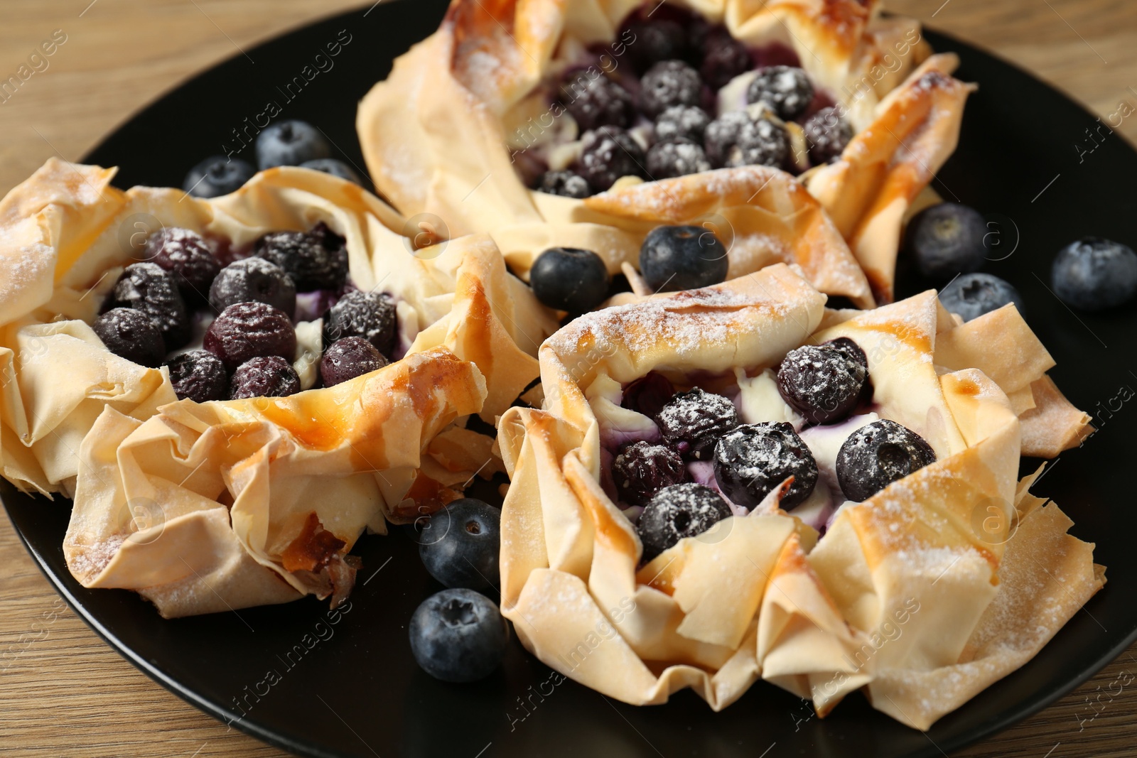 Photo of Tasty puff pastries with blueberries on table, closeup