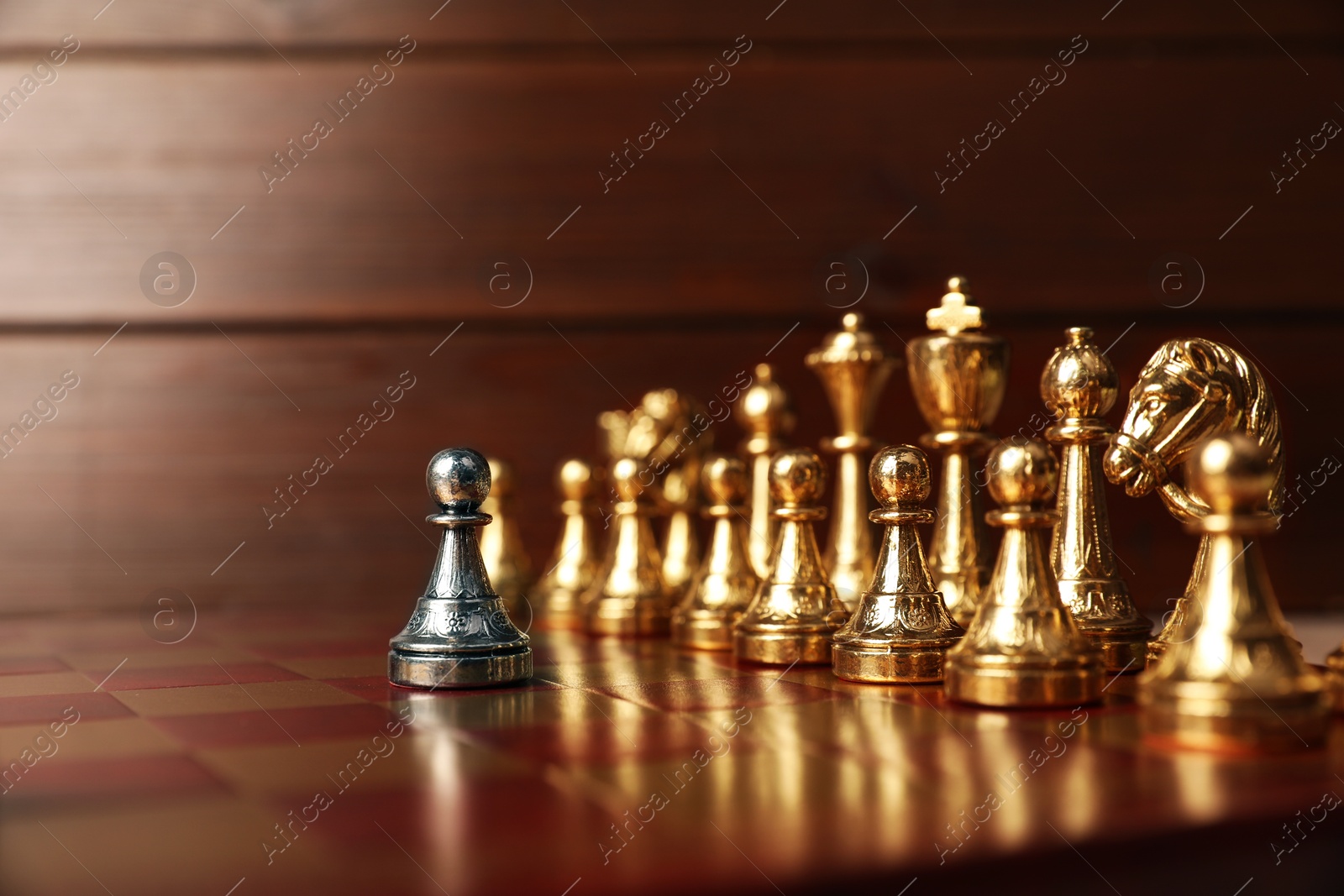 Photo of Silver pawn in front of other chess pieces on chessboard. Competition concept