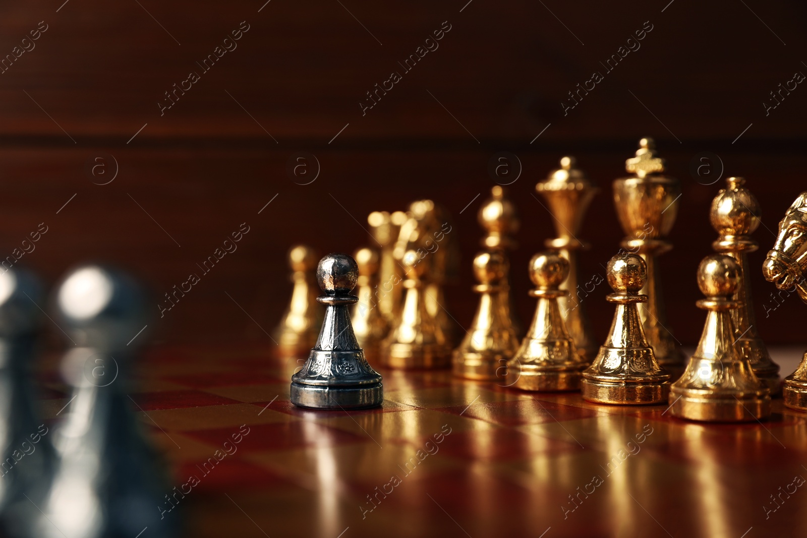 Photo of Silver pawn in front of other chess pieces on chessboard. Competition concept