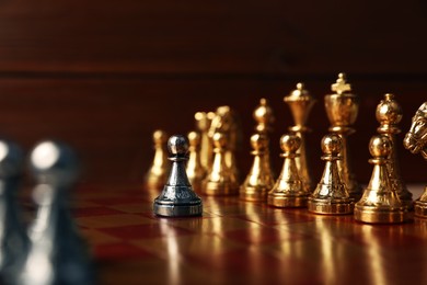 Photo of Silver pawn in front of other chess pieces on chessboard. Competition concept