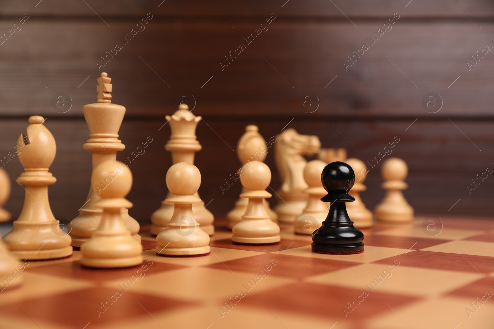 Photo of Black pawn in front of other chess pieces on chessboard. Competition concept