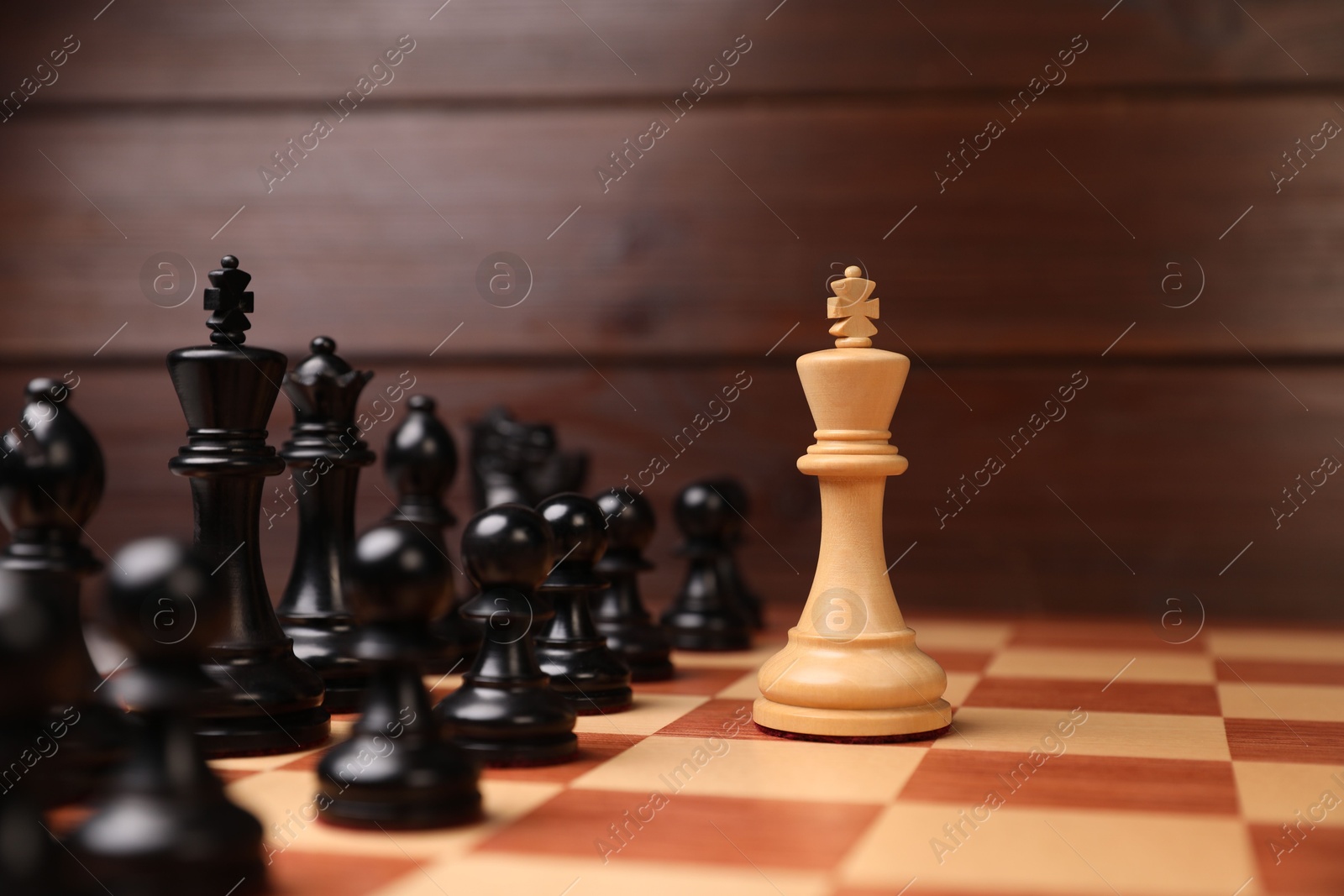 Photo of White king in front of other chess pieces on chessboard. Competition concept