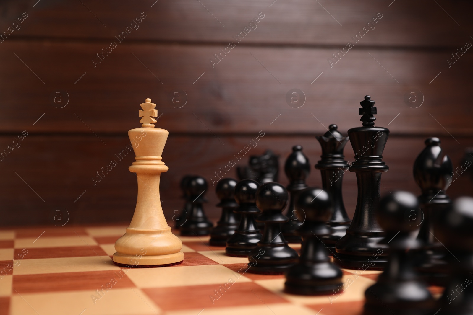 Photo of White king in front of other chess pieces on chessboard. Competition concept