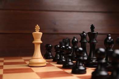 Photo of White king in front of other chess pieces on chessboard. Competition concept