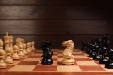 Photo of Black and white chess knights in middle of chessboard. Competition concept