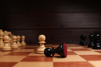 Photo of White pawn and fallen black one in middle of chessboard, closeup. Competition concept