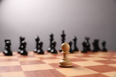 Photo of White pawn in front of other black chess pieces on chessboard, closeup. Competition concept