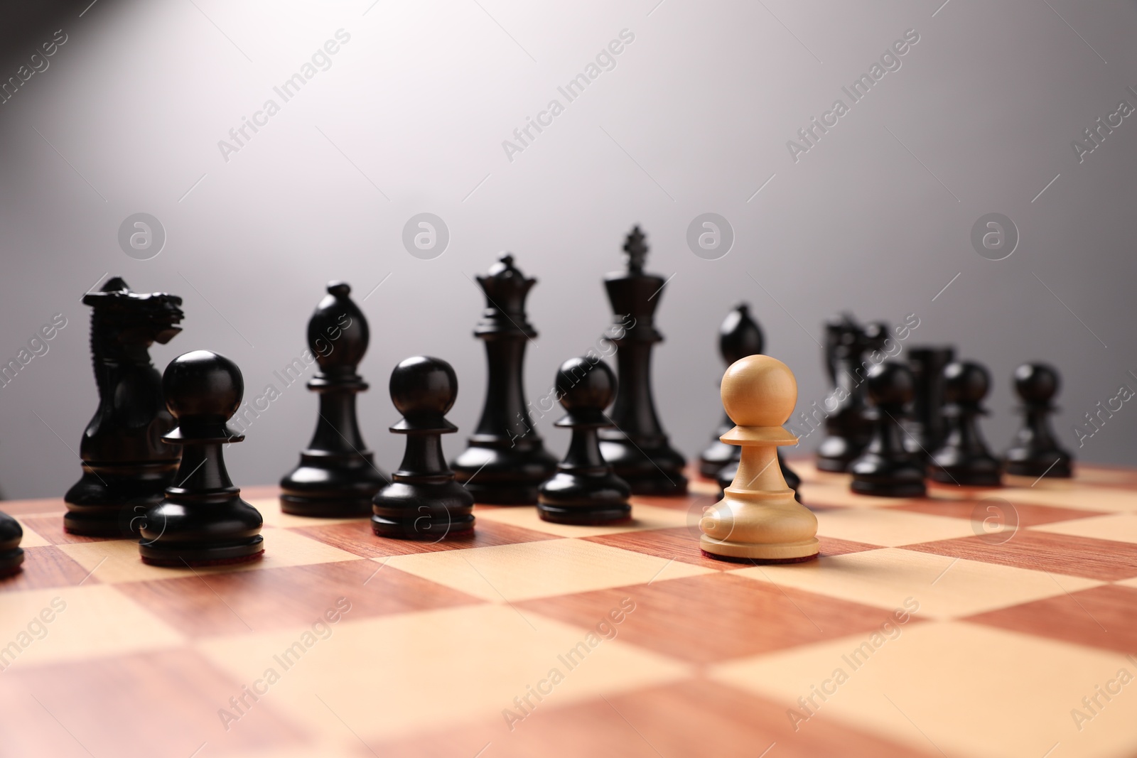 Photo of White pawn in front of black ones on chessboard. Competition concept