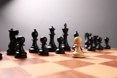 Photo of White pawn in front of black ones on chessboard. Competition concept