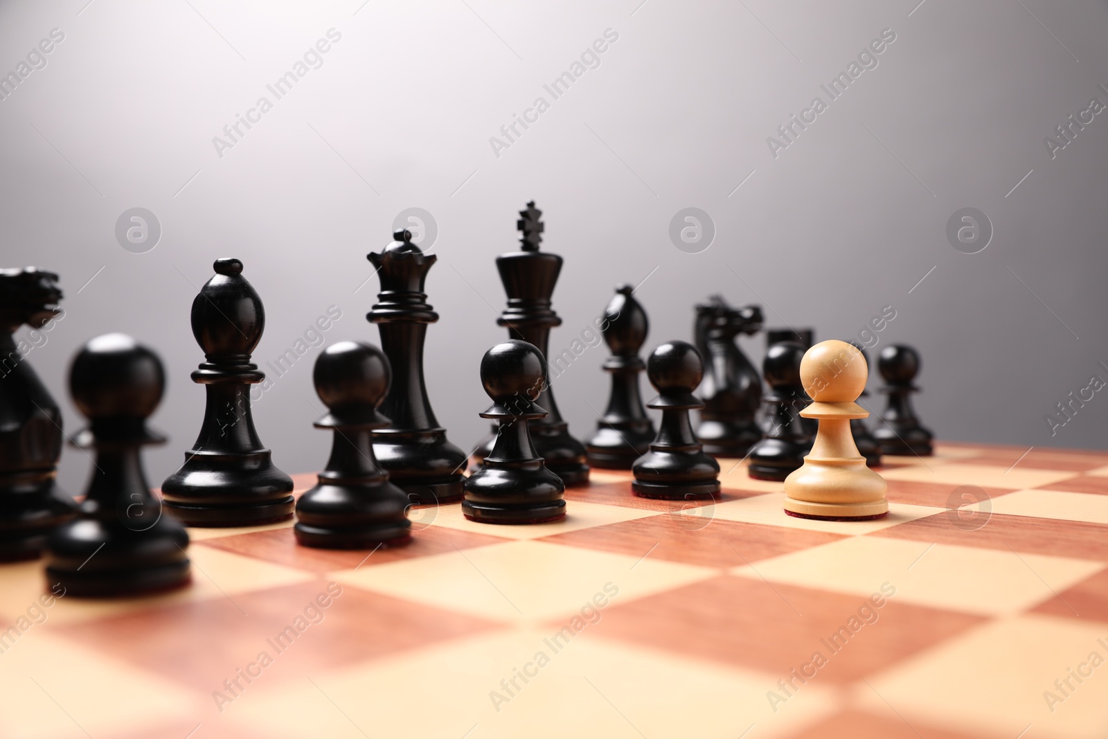 Photo of White pawn in front of black ones on chessboard. Competition concept