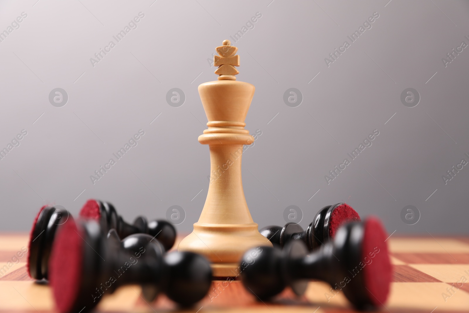 Photo of White chess king among fallen black pawns on chessboard, closeup. Competition concept