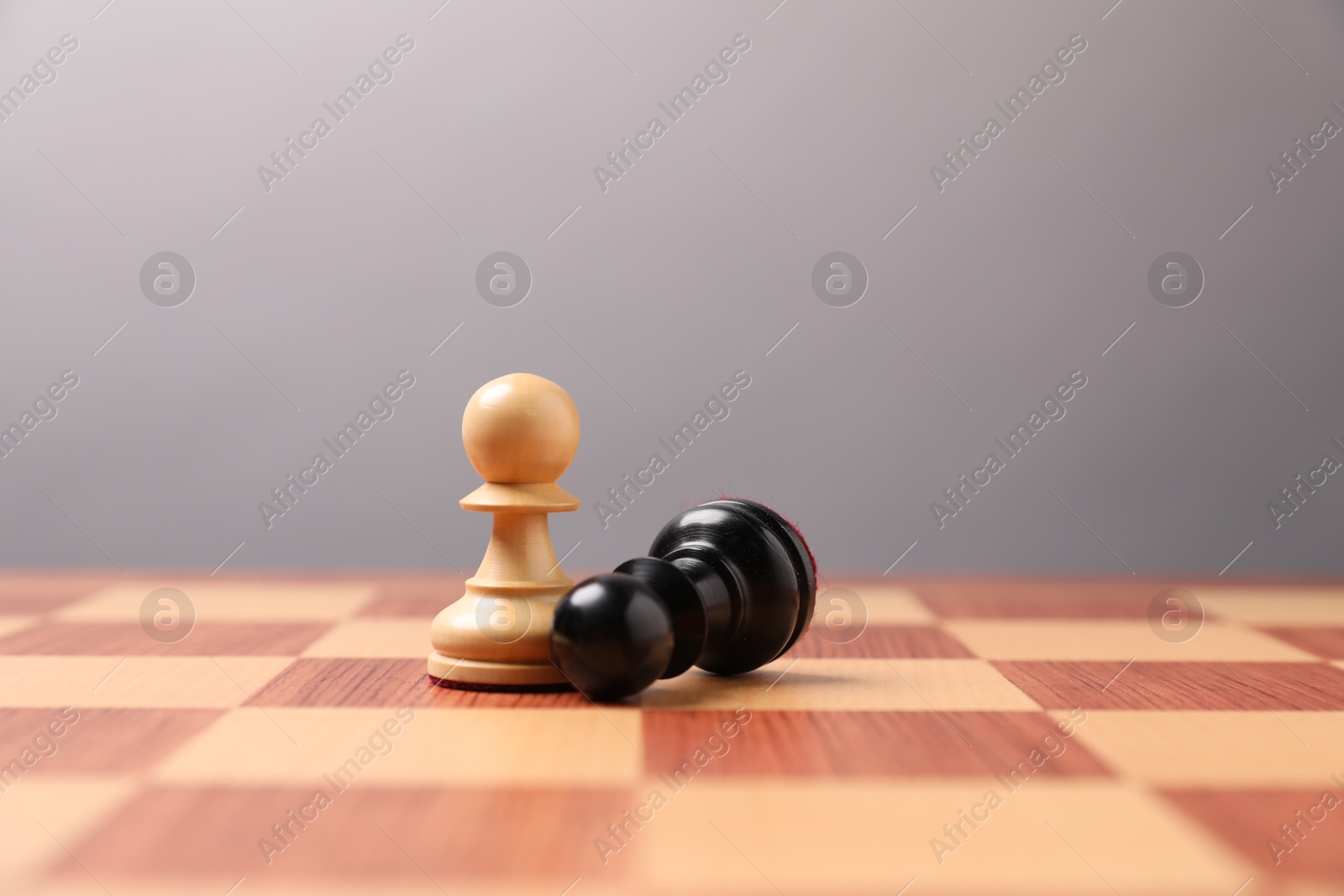 Photo of White pawn near fallen black one in middle of chessboard. Competition concept