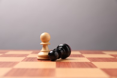 Photo of White pawn near fallen black one in middle of chessboard. Competition concept