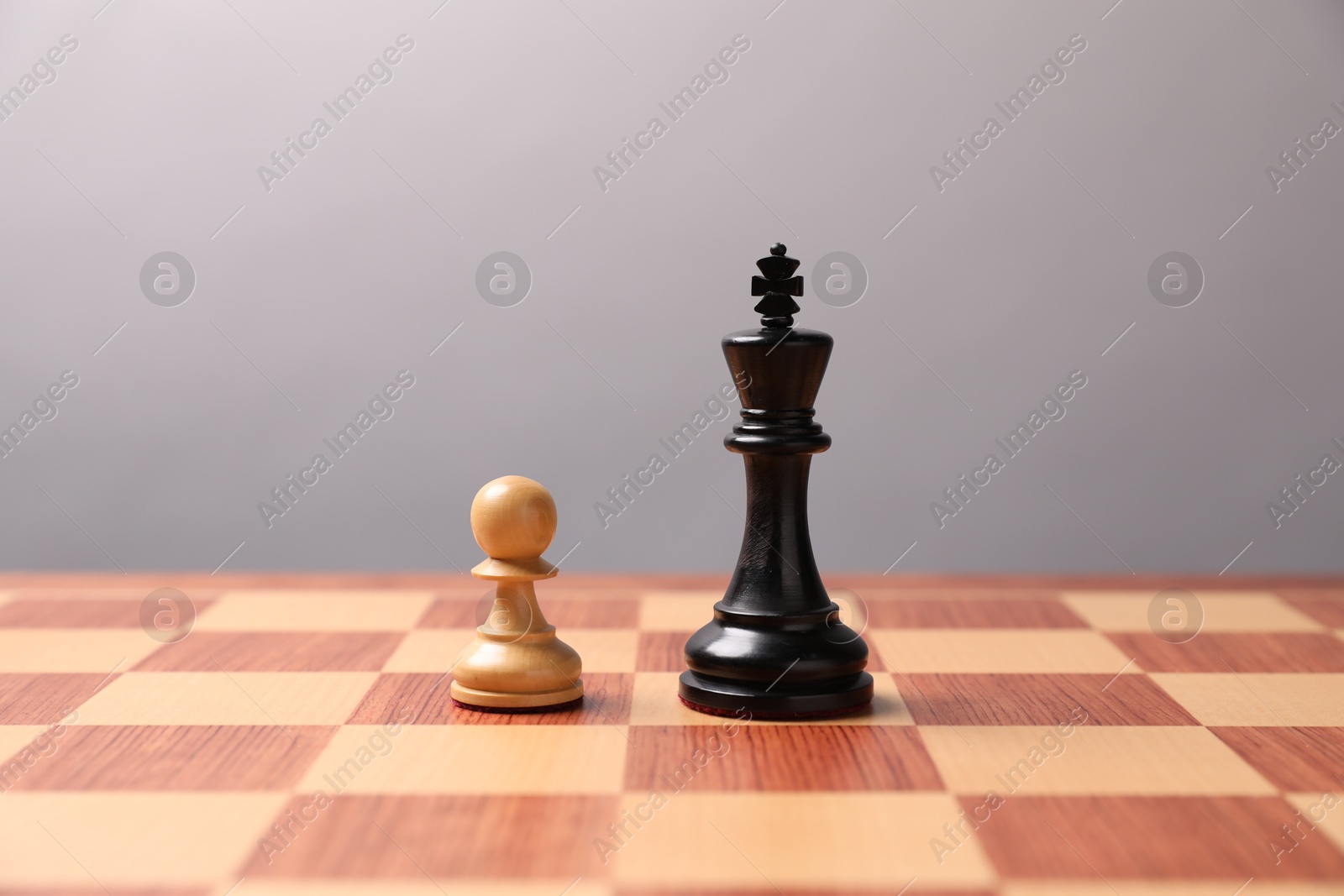 Photo of Black chess king and white pawn in middle of chessboard. Competition concept