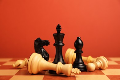 Photo of Black chess pieces among other fallen white ones on chessboard, closeup. Competition concept