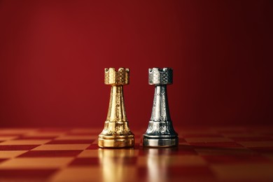 Photo of Golden and silver chess rooks in middle of chessboard. Competition concept