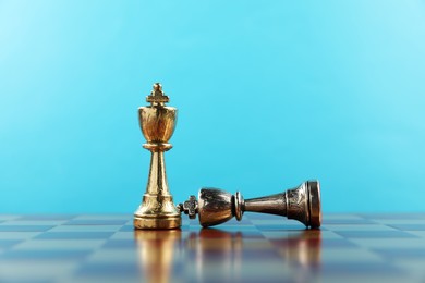 Photo of Golden chess king near fallen silver one in middle of chessboard. Competition concept