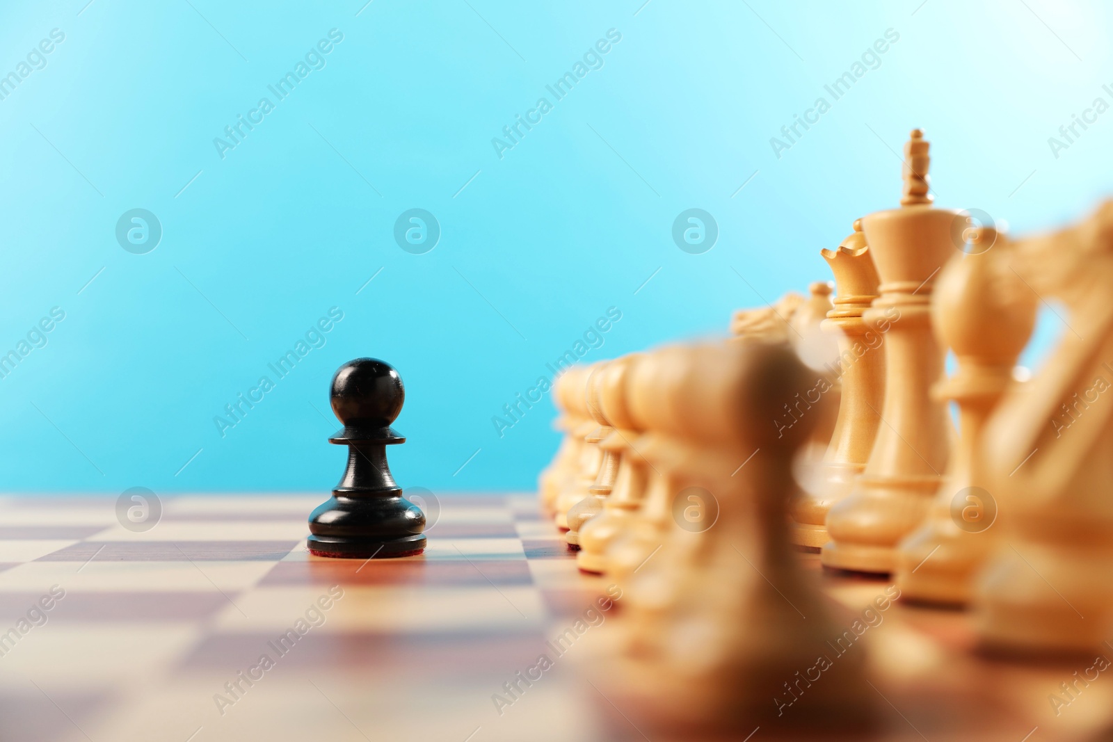 Photo of Black pawn in front of other white chess pieces on chessboard. Competition concept