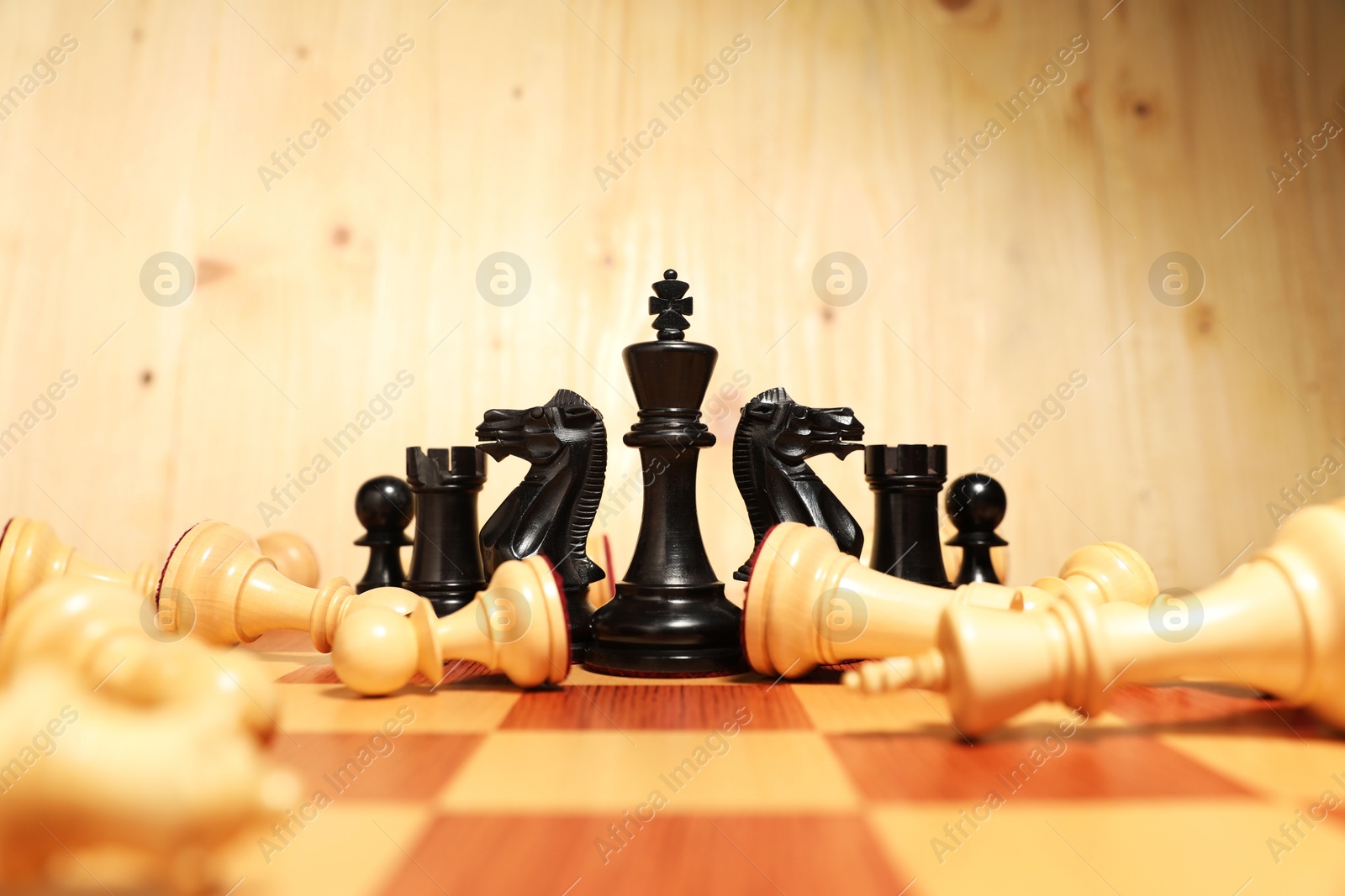 Photo of Black chess king among other fallen white game pieces on chessboard. Competition concept