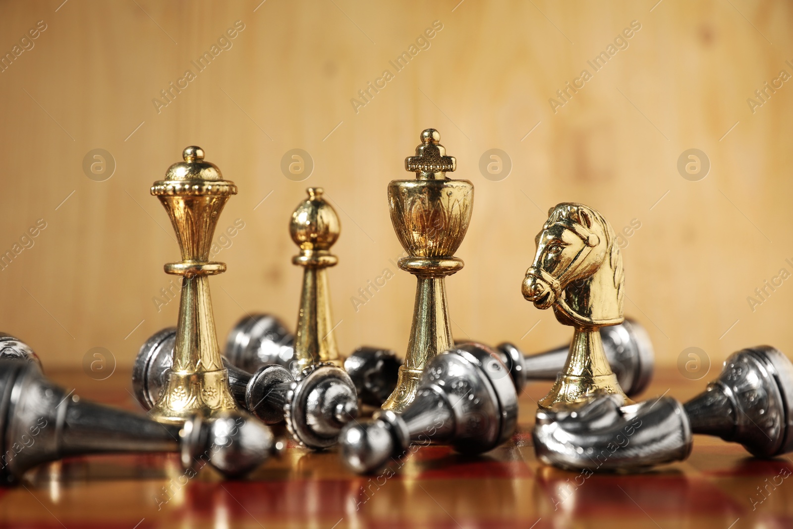 Photo of Golden chess pieces among fallen silver ones on chessboard, closeup. Competition concept