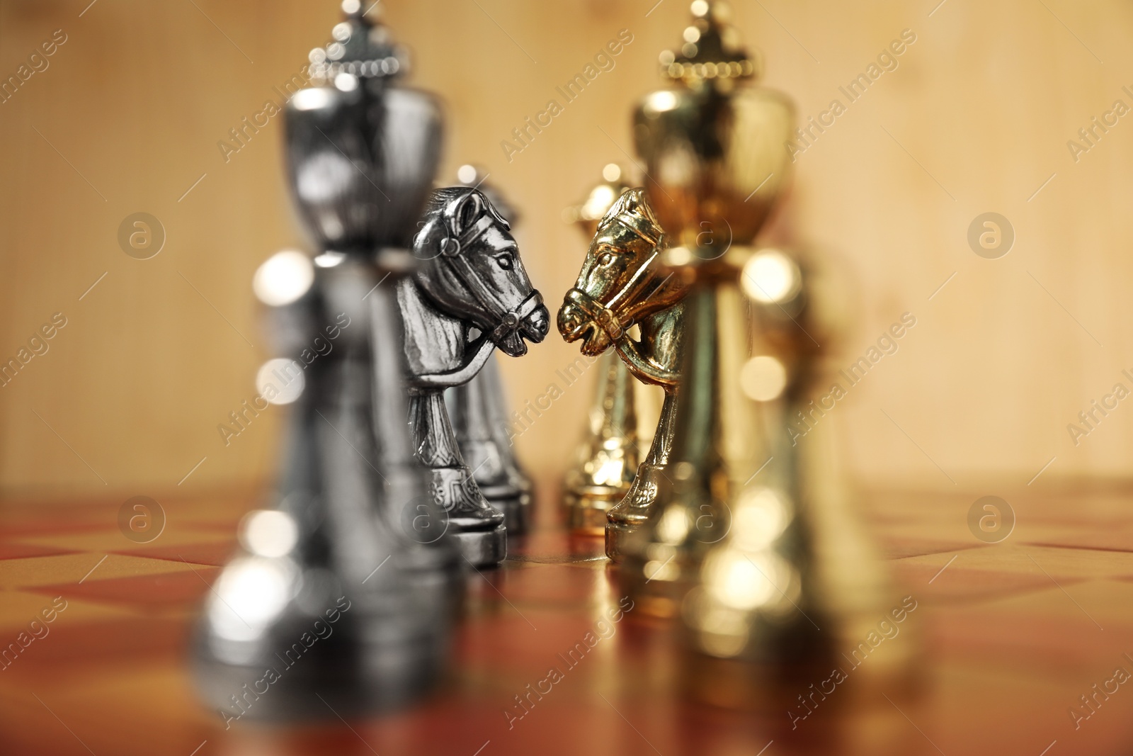 Photo of Golden and silver chess pieces on chessboard, closeup. Competition concept