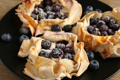 Photo of Tasty puff pastries with blueberries on table, closeup