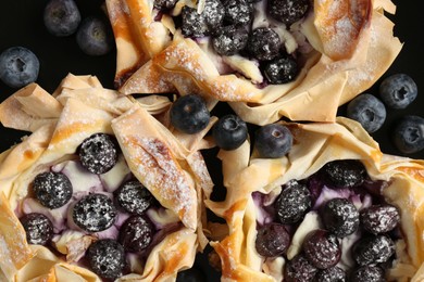 Photo of Tasty puff pastries with blueberries on plate, top view