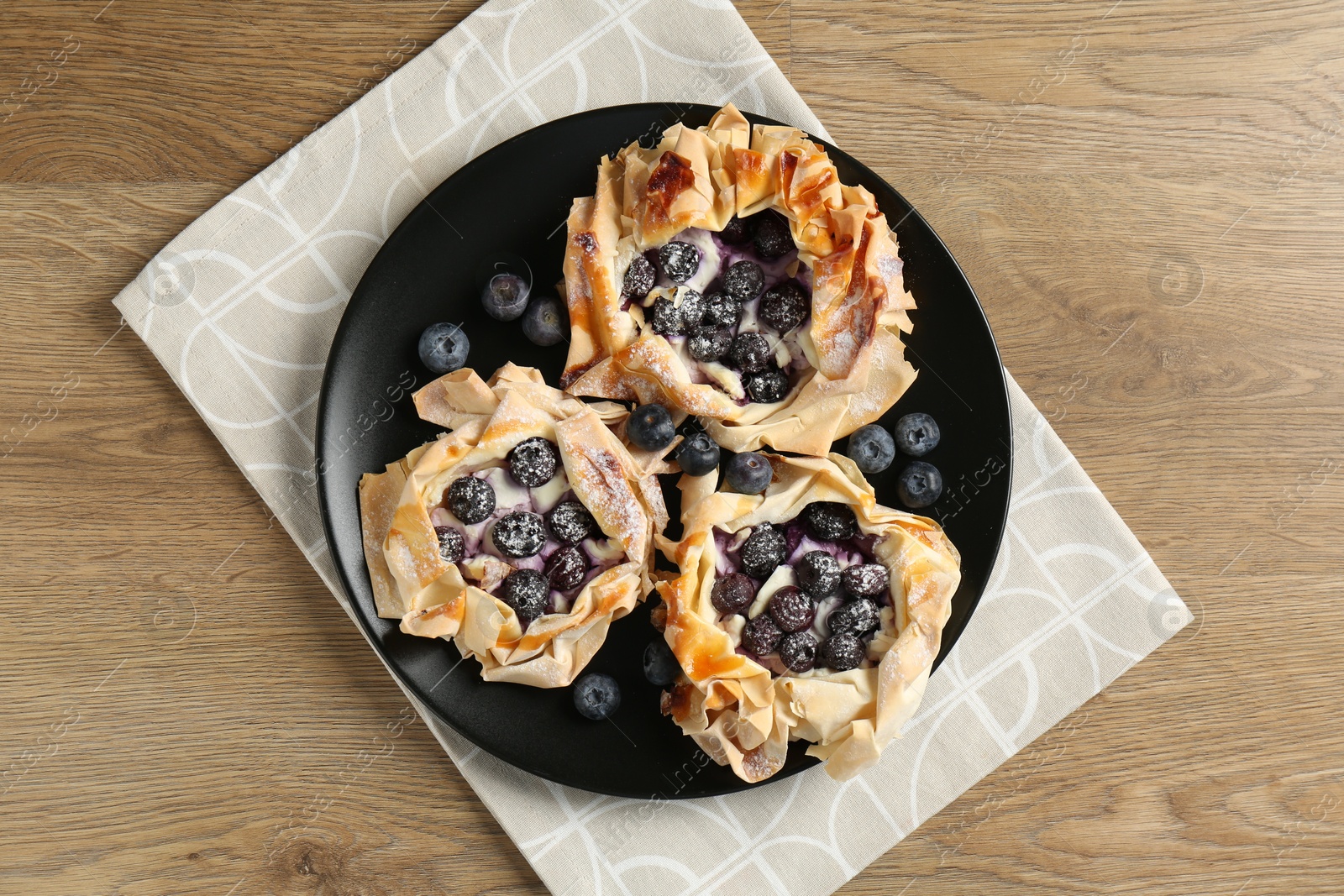 Photo of Tasty puff pastries with blueberries on wooden table, top view