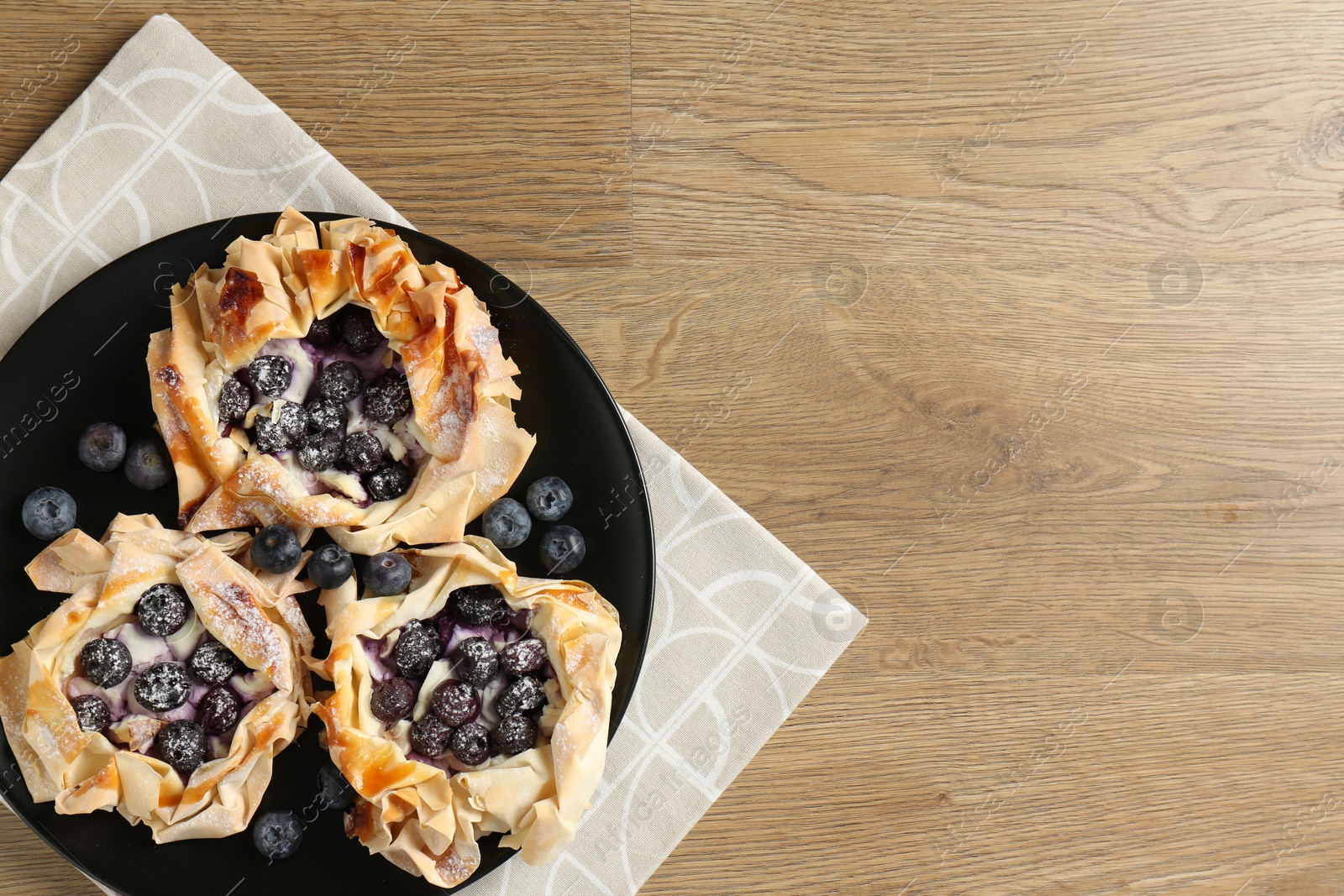 Photo of Tasty puff pastries with blueberries on wooden table, top view. Space for text