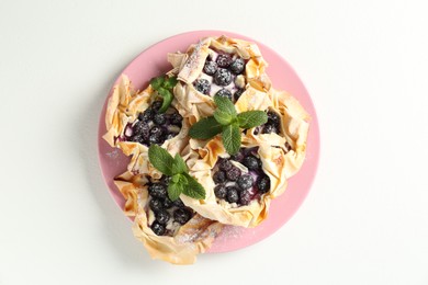 Photo of Tasty puff pastries with blueberries, powdered sugar and mint on white table, top view