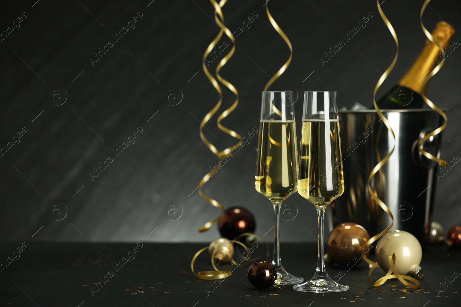 Photo of Champagne in glasses and decor on black table, space or text. Christmas celebration