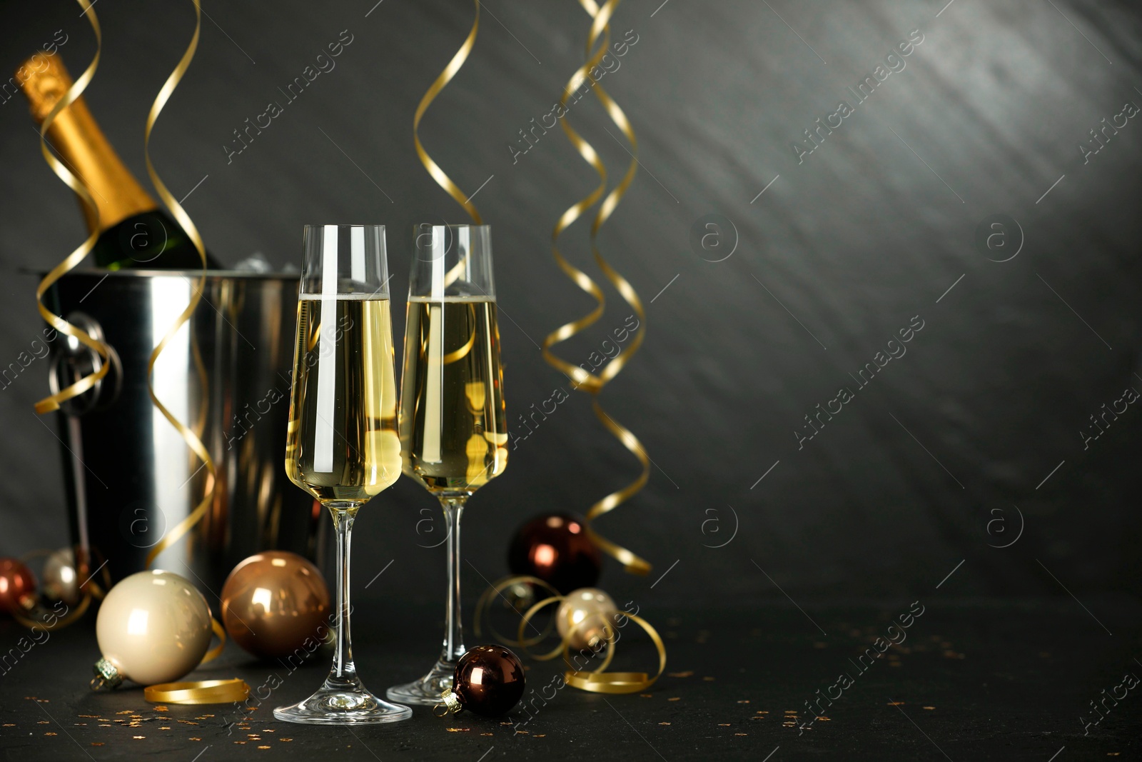 Photo of Champagne in glasses and decor on black table, space or text. Christmas celebration