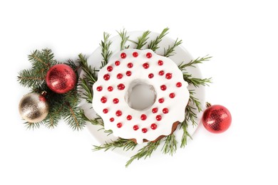 Photo of Beautifully decorated Christmas cake, fir branches and baubles on white background, top view