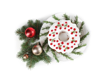 Photo of Beautifully decorated Christmas cake, fir branches and baubles on white background, top view