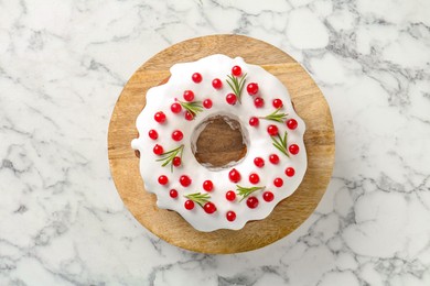 Photo of Traditional Christmas cake decorated with red currants and rosemary on white marble table, top view