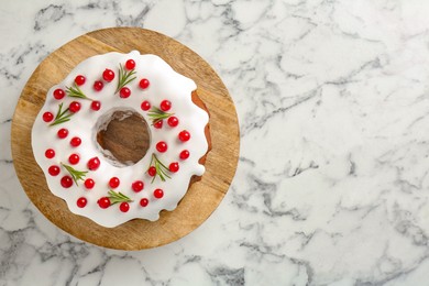 Photo of Traditional Christmas cake decorated with red currants and rosemary on white marble table, top view. Space for text